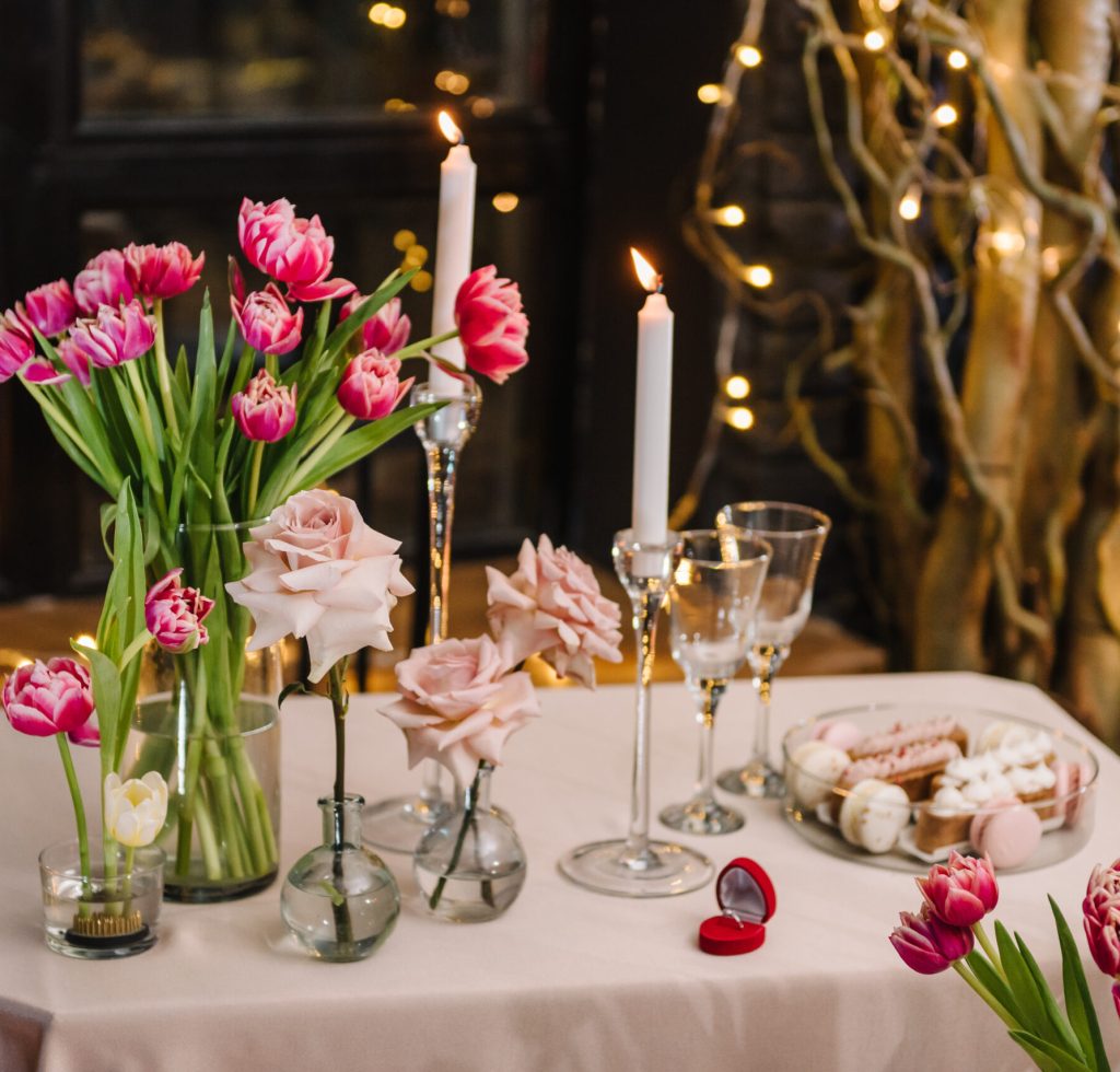 Table setting in restaurant. Romantic date. Luxury candlelight dinner setup table for couple on Valentine's day. Location decoration tulips flowers, decor candles for surprise marriage proposal.